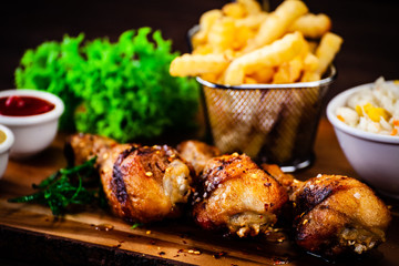 Roast chicken drumsticks with french fries on black stone board