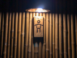 Sign of genderman in front of classic bamboo vintage and retro toilet indoor with lowlight.