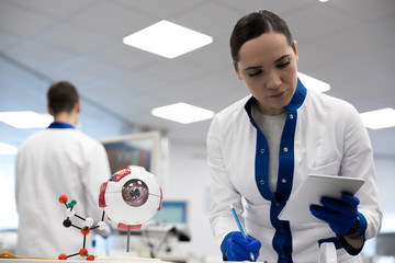Female scientist holding digital tablet and making notes