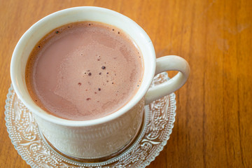 Hot chocolate drink (minuman coklat) in a white cup on wooden background