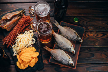 Two mugs of light beer and selection of beer snacks on the table. Oktoberfest food, pub concept
