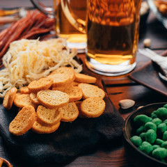 Two mugs of light beer and selection of beer snacks on the table. Oktoberfest food, pub concept
