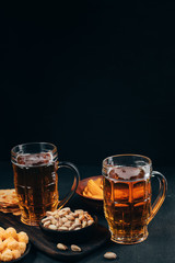 Appetizing salty beer snacks. Two mugs of craft lager, chips and pistachios. Oktoberfest food, pub concept