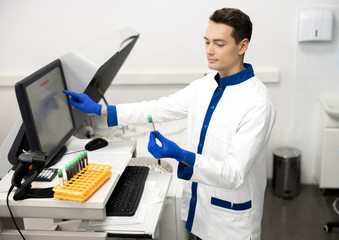 Handsome male researcher doing biochemical blood test in lab