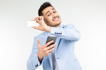 smiling businessman in a blue jacket with a credit card with a mockup and a smartphone in hand on a white studio background