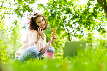 Pretty young caucasian woman go for a walk at park with coffee and laptop