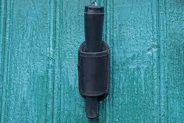 one black pinpointer in a case hangs on a green wooden wall