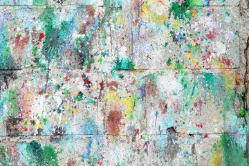 Old cement block wall texture with colorful painted drops on colorful bright background