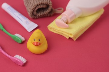 Obraz na płótnie Canvas Spa and bath concept. Baby bath set. Cute child spa composition on bright pink background. Soap bottle, towel, washcloth, rubber duck toy and toothbrushes. Copy space for text. Selective focus.