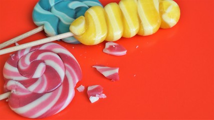 multi-colored caramel on wooden sticks of various shapes on a red background