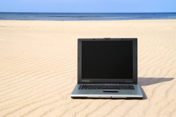 Modern laptop lying on beach