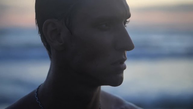 Portrait close up of a young caucasian man enjoying free time on a beach by the sea at sunset on the evening