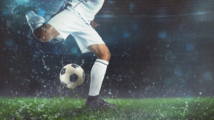 Close up of a soccer scene at night match with player in a white uniform kicking the ball with power