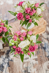 Vertical shot arrangement of flowers. Beautiful handmade bouquet of roses and greenery in a large cup on a rustic background. Great gift for Mothers Day, March 8 or Valentines Day