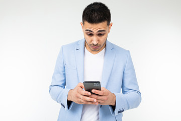 businessman in a blue jacket looks suspiciously at a smartphone on a white background