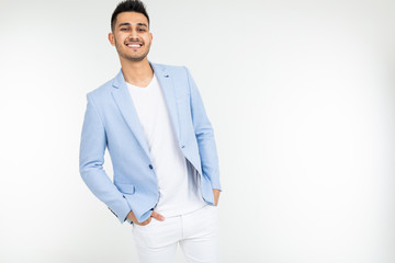 handsome guy in a blue jacket with a beautiful smile tucked his hands in pants on a white isolated background with copy space