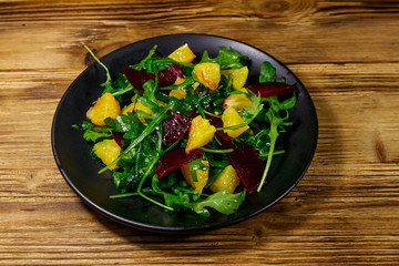 Tasty salad of fresh arugula, beetroot and oranges on wooden table. Healthy food or vegetarian concept