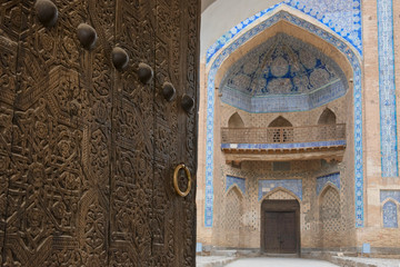 Fototapeta na wymiar Ajar old wooden door (with copper handle) of Mohammed Rakhim Khan Madrasah. Khiva, Uzbekistan.