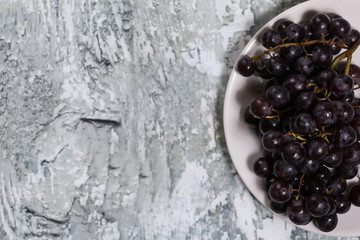 Red grape on a plate on a wooden background.