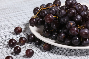 Red grape on a plate on a kitchen background.