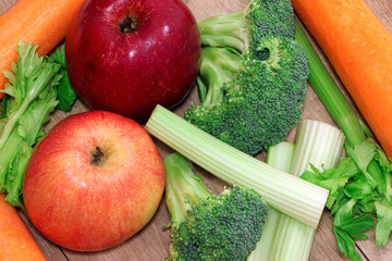 Fresh vegetables and fruits on a wooden table. Healthy, vegetarian food. Natural vitamins. Carrot, broccoli, apples and celery. Vegetables on a tray. Flat lay.