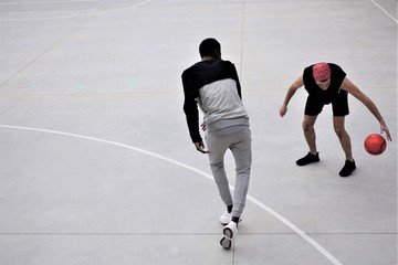 Fototapeta premium Two basketball players of different ethnicity play a training match on a street court. Sports training concept