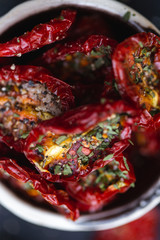Close up of dried dehydrated red tomatoes with spices on top, view from above.