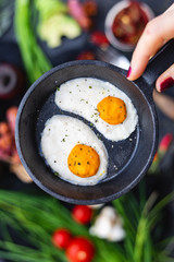 Female hand holding a frying pan with raw vegan eggs made of coconut butter and cashew. Raw food for vegan menu.