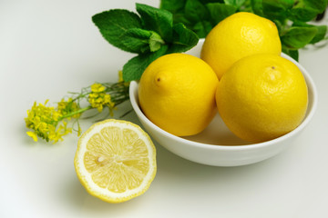 Fototapeta na wymiar Composition with lemons in white bowl on white background.