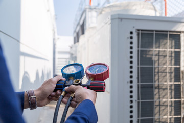 Technician is checking air conditioner ,measuring equipment for filling air conditioners.