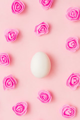 White egg among flowers on a pink background. Easter concept