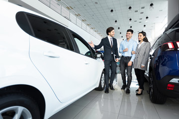 Car Sales Manager Showing Auto To Buyers In Dealership Store