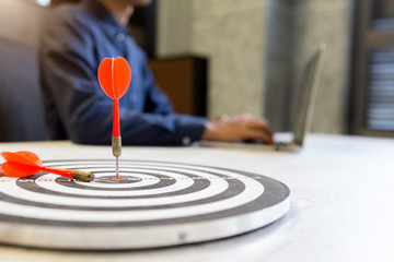 Fototapeta premium Red dart arrow hitting in the target center of dartboard on bullseye,business growth success concept.