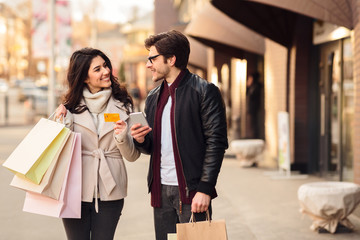 Couple with smartphone and credit card near city center