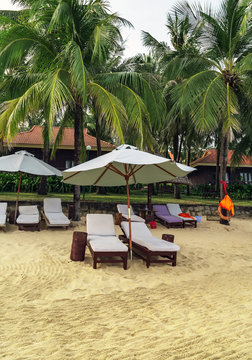 Long Beach, Phu Quoc Island, Vietnam. Nobody on the beach. Palm tree bamboo umbrellas and sun chairs in background.