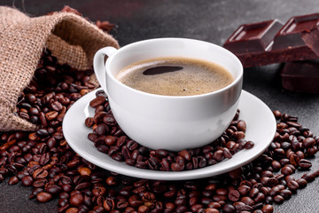 A cup of fresh scented morning coffee for a cheerful start to the day. Beautiful coffee cup with coffee on a dark table