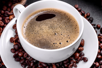 A cup of fresh scented morning coffee for a cheerful start to the day. Beautiful coffee cup with coffee on a dark table