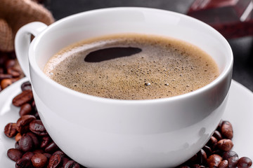 A cup of fresh scented morning coffee for a cheerful start to the day. Beautiful coffee cup with coffee on a dark table
