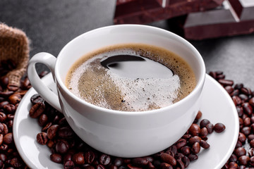 A cup of fresh scented morning coffee for a cheerful start to the day. Beautiful coffee cup with coffee on a dark table