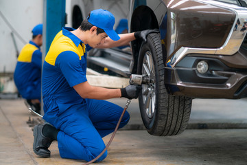 Fototapeta na wymiar Asian Mechanician changing car wheel in auto repair shop