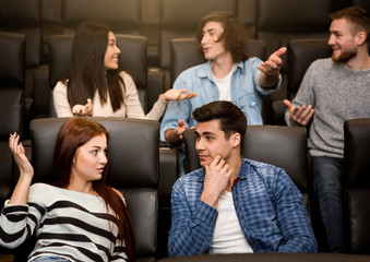 Young friends talking while waiting for film to start in cinema