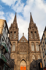 Fototapeta na wymiar Beautiful, impressive cathedral of Clermont Ferrand in France, made from dark volcanic rocks lighten by golden sunset sun light and old, traditional French buildings