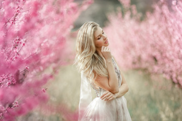 Beautiful woman dressed in a dress against the background of trees. Elegance blonde dressed in a retro dress in a flowering garden