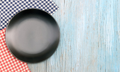 black plate on tablecloth on wood table background