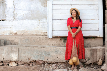 A woman stands near a white wooden wall and smiles into the distance.