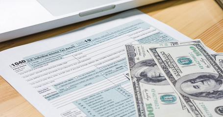 U.S. 1040 tax return form with 100 usd dollar bills.