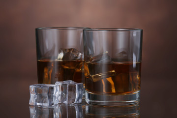 Glasses of whiskey on brown background