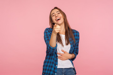 Hey, you are ridiculous! Joyful girl in checkered shirt laughing, holding stomach and pointing to camera, taunting you, can't stop hysterical laughter. indoor studio shot isolated on pink background