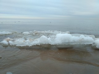 Snow and waves breaking on beach