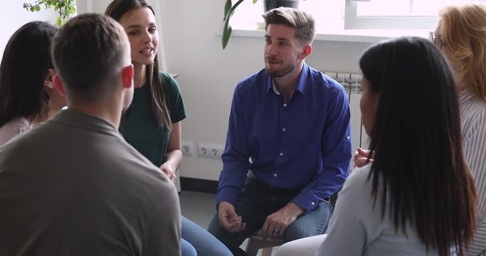 Diverse people sitting in circle, sharing personal problems at psychotherapy session. Male psychologist therapist helping multiracial younger and older patients at group therapy, rehab concept.